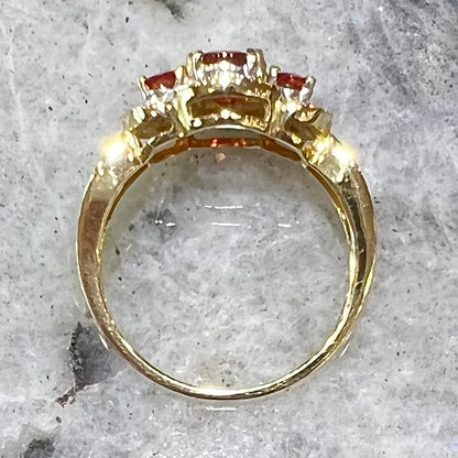 Past, present, future style red andesine feldspar and diamond halo ring cast in 14kt yellow gold.