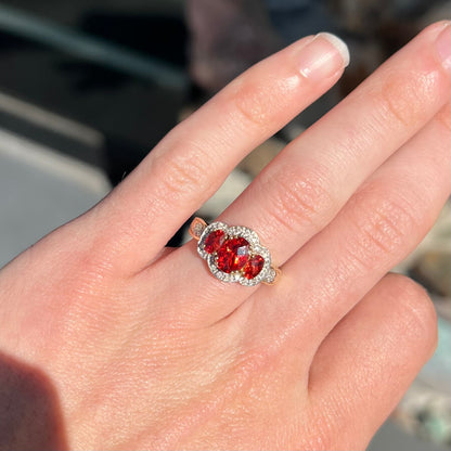 Past, present, future style red andesine feldspar and diamond halo ring cast in 14kt yellow gold.