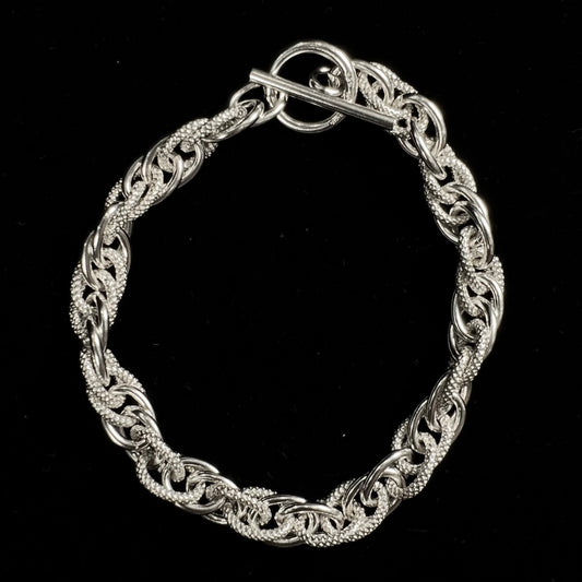 A silver toggle clasp link bracelet.  Some of the links are textured, and others are polished.  The toggle ring is stamped "India."