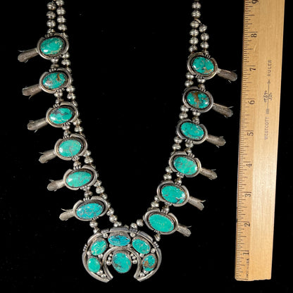 A silver Kingman turquoise squash blossom necklace.  The necklace is made with handmade Navajo pearls.