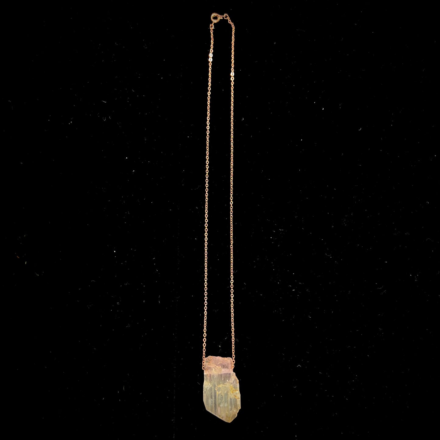 A drilled bicolor spodumene crystal hanging on a copper cable chain.  The crystal is pink and yellow, or kunzite and triphane respectively.