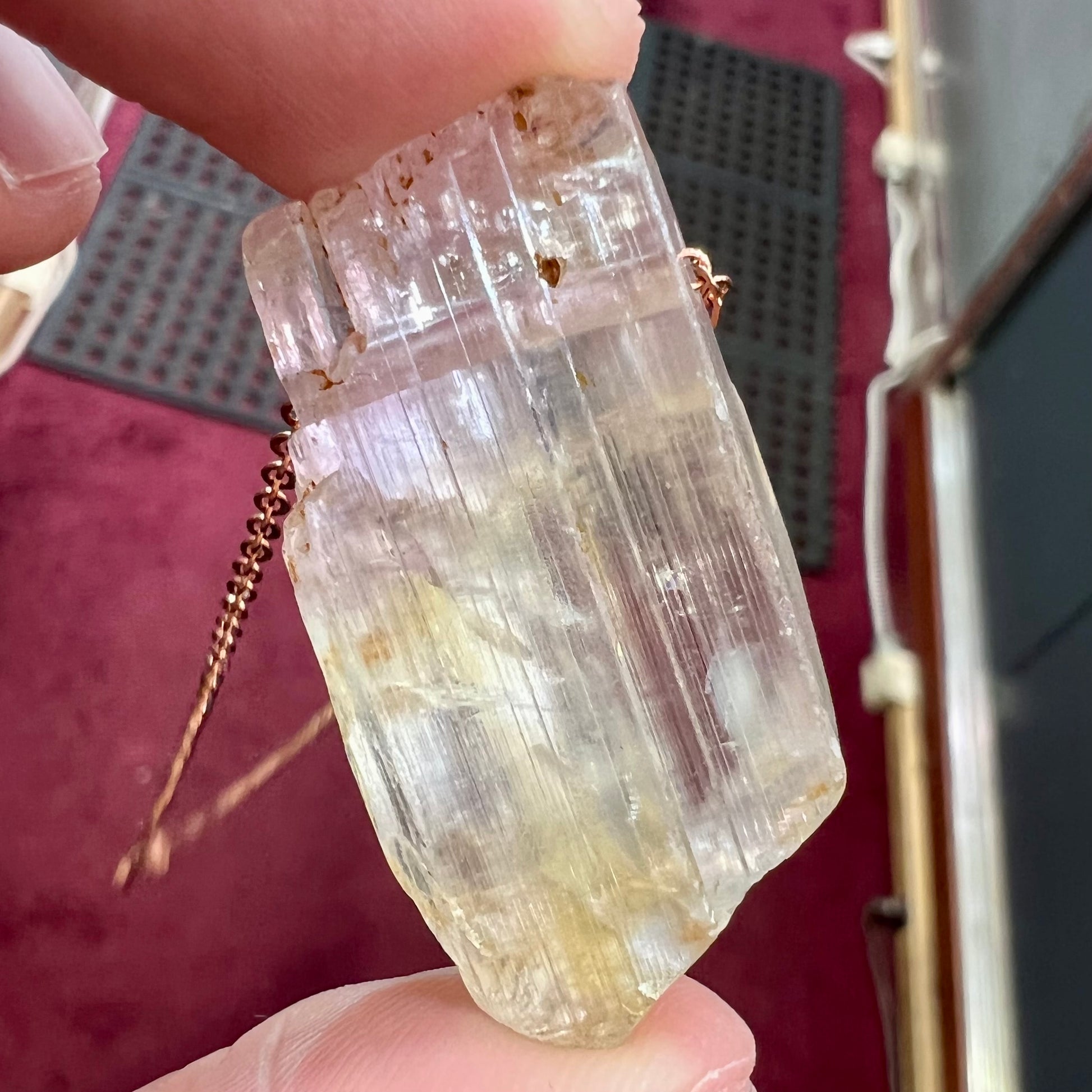 A drilled bicolor spodumene crystal hanging on a copper cable chain.  The crystal is pink and yellow, or kunzite and triphane respectively.