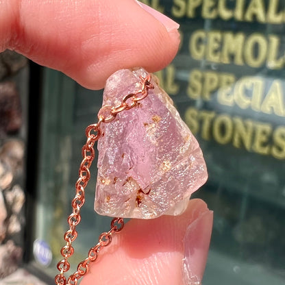 A drilled bicolor spodumene crystal hanging on a copper cable chain.  The crystal is pink and yellow, or kunzite and triphane respectively.