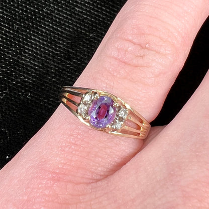 A ladies split shank gold ring set with an oval cut amethyst and round brilliant diamond accents.