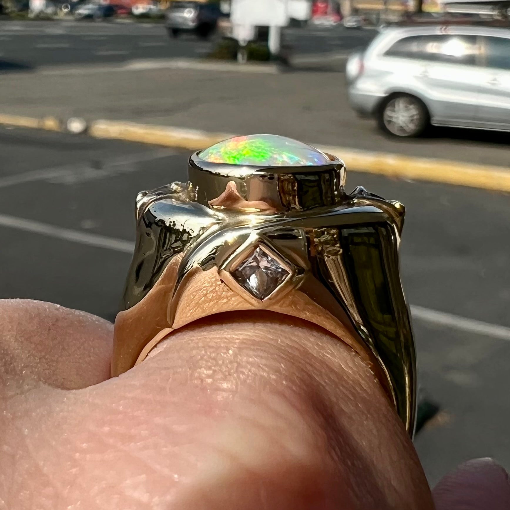 A yellow gold men's opal ring set with princess cut white sapphires.