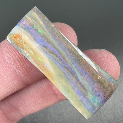 A polished, tapered rectangular cut boulder opal stone from Quilpie, Australia.