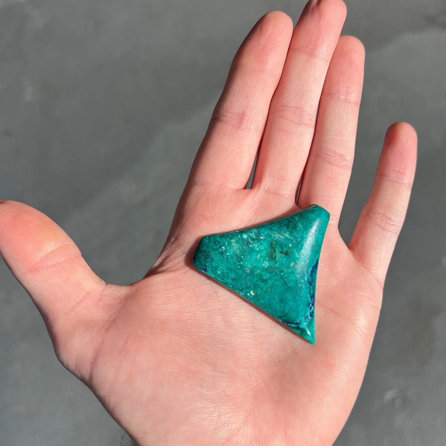 Loose polished green chrysocolla stone with blue azurite inclusions.