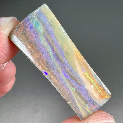 A polished, tapered rectangular cut boulder opal stone from Quilpie, Australia.