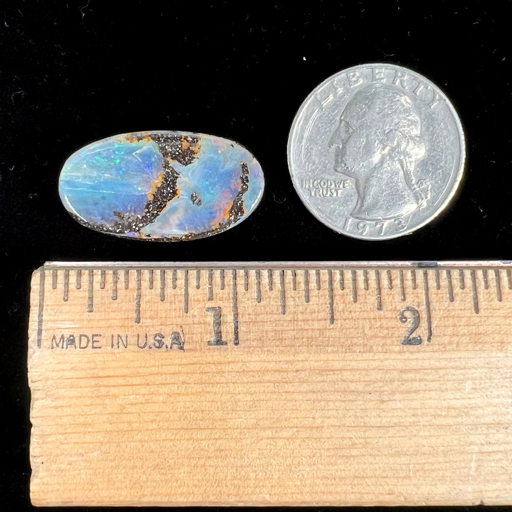 A loose, oval cabochon cut boulder opal stone from Queensland, Australia.