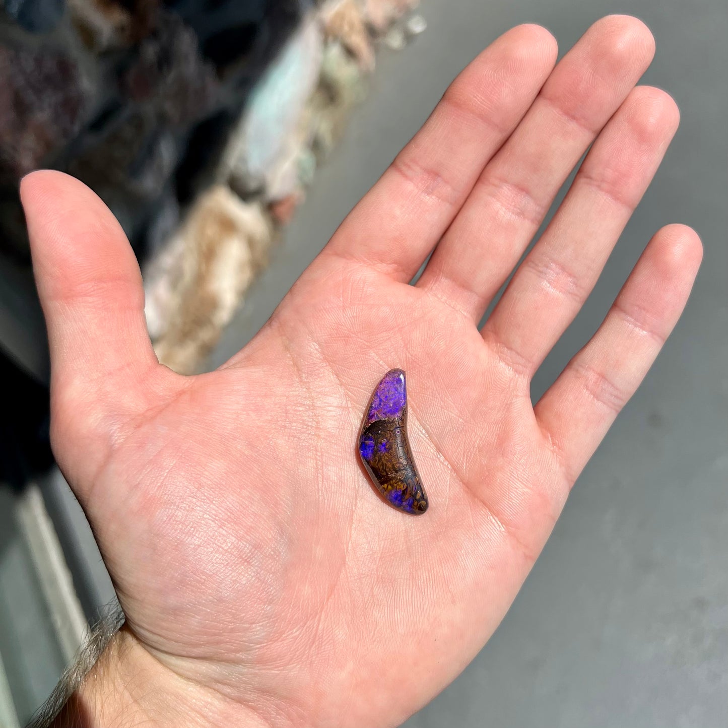 A loose boomerang shaped purple boulder opal stone from Quilpie, Australia.