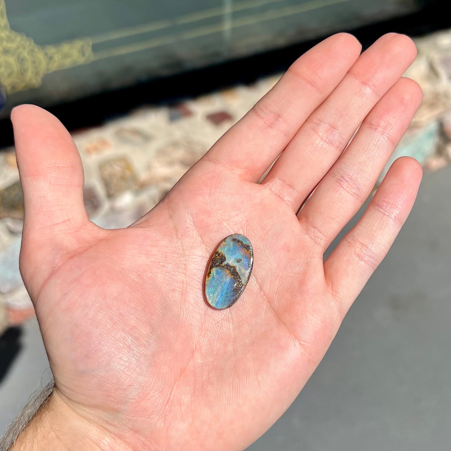 A loose, oval cabochon cut boulder opal stone from Queensland, Australia.