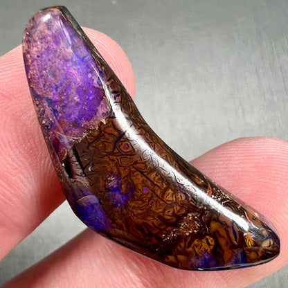 A loose boomerang shaped purple boulder opal stone from Quilpie, Australia.