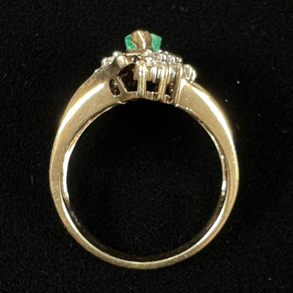 A yellow gold marquise cut emerald and diamond ring.  The diamonds are prong set round cuts and channel set baguette cuts.