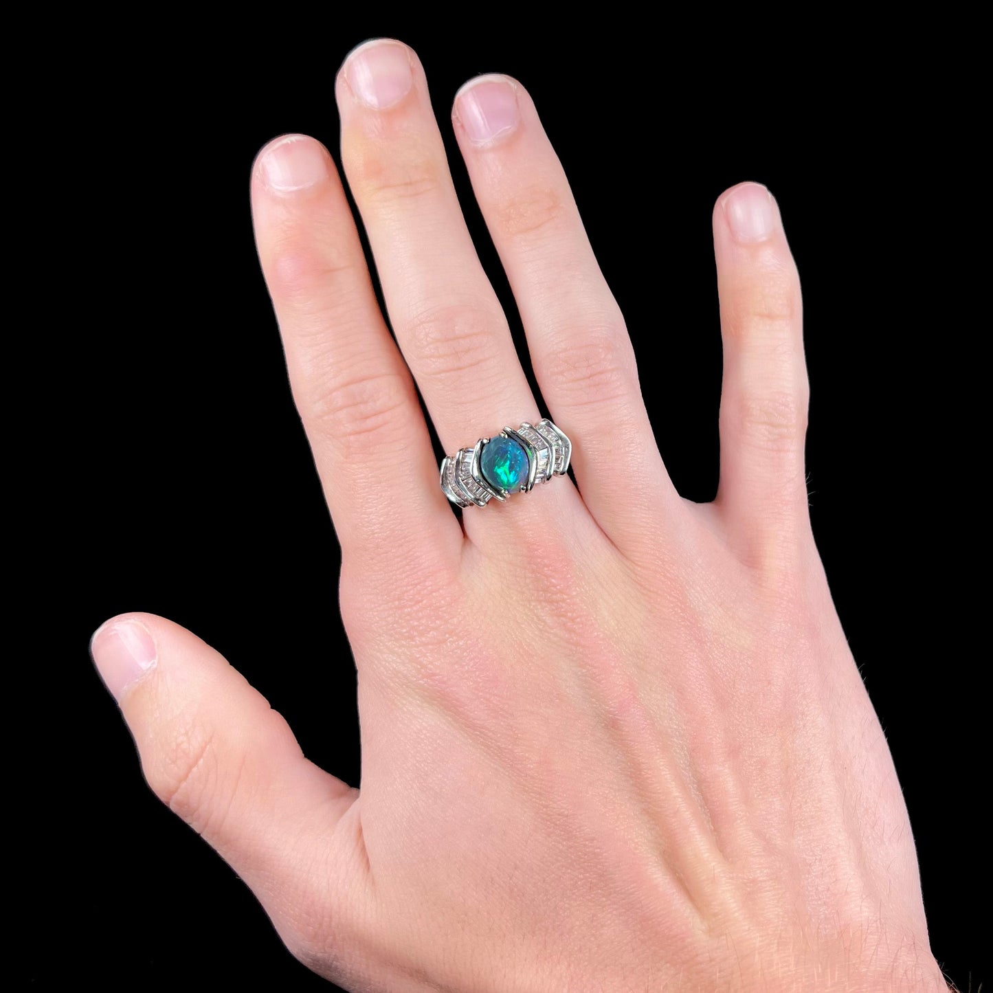 A white gold ring set with a Lightning Ridge natural black opal and baguette cut diamonds.