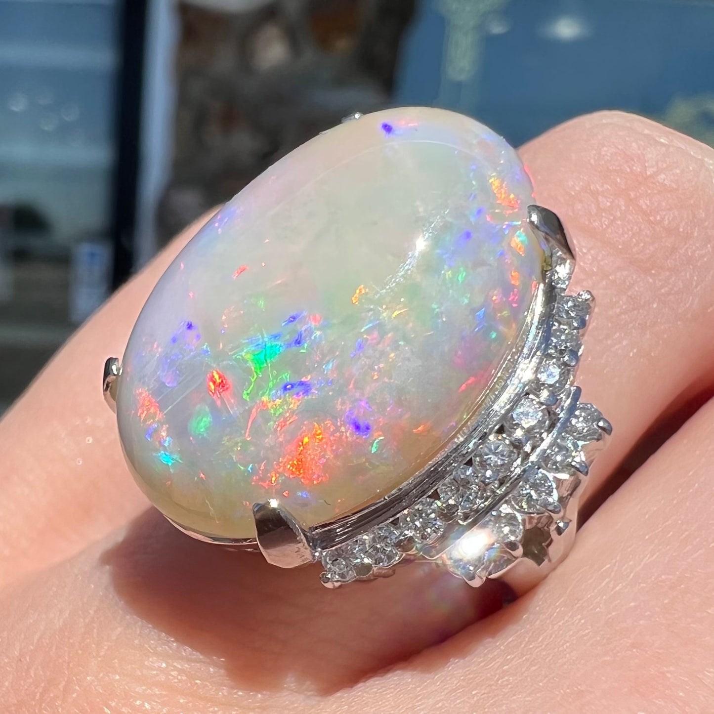 An oval cabochon cut Coober Pedy, Australian opal prong set in a platinum ring with round cut diamonds.