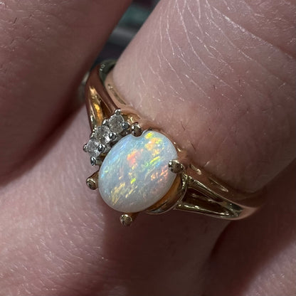 A ladies' yellow gold Coober Pedy, Australian opal ring set with three round cut diamonds.