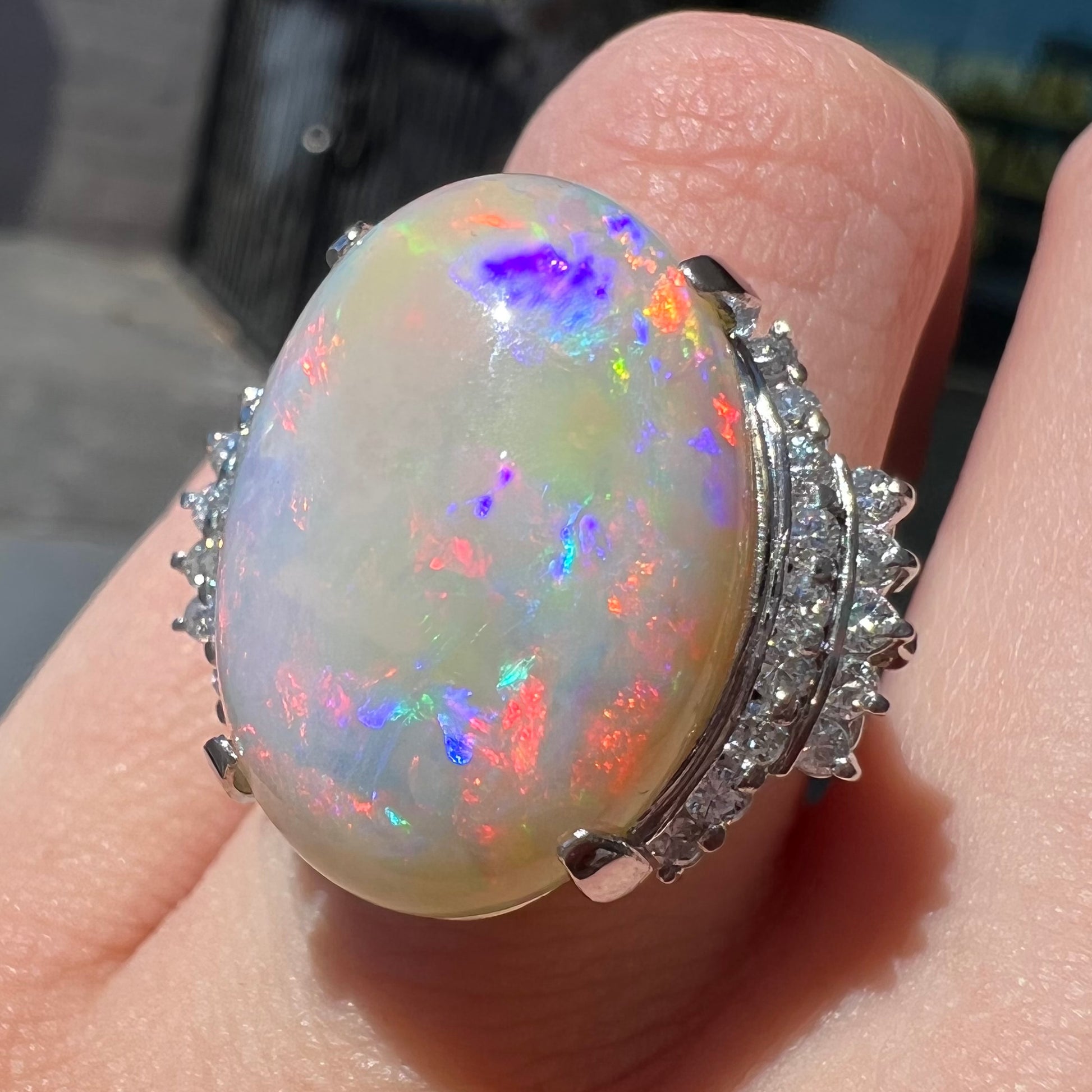 An oval cabochon cut Coober Pedy, Australian opal prong set in a platinum ring with round cut diamonds.