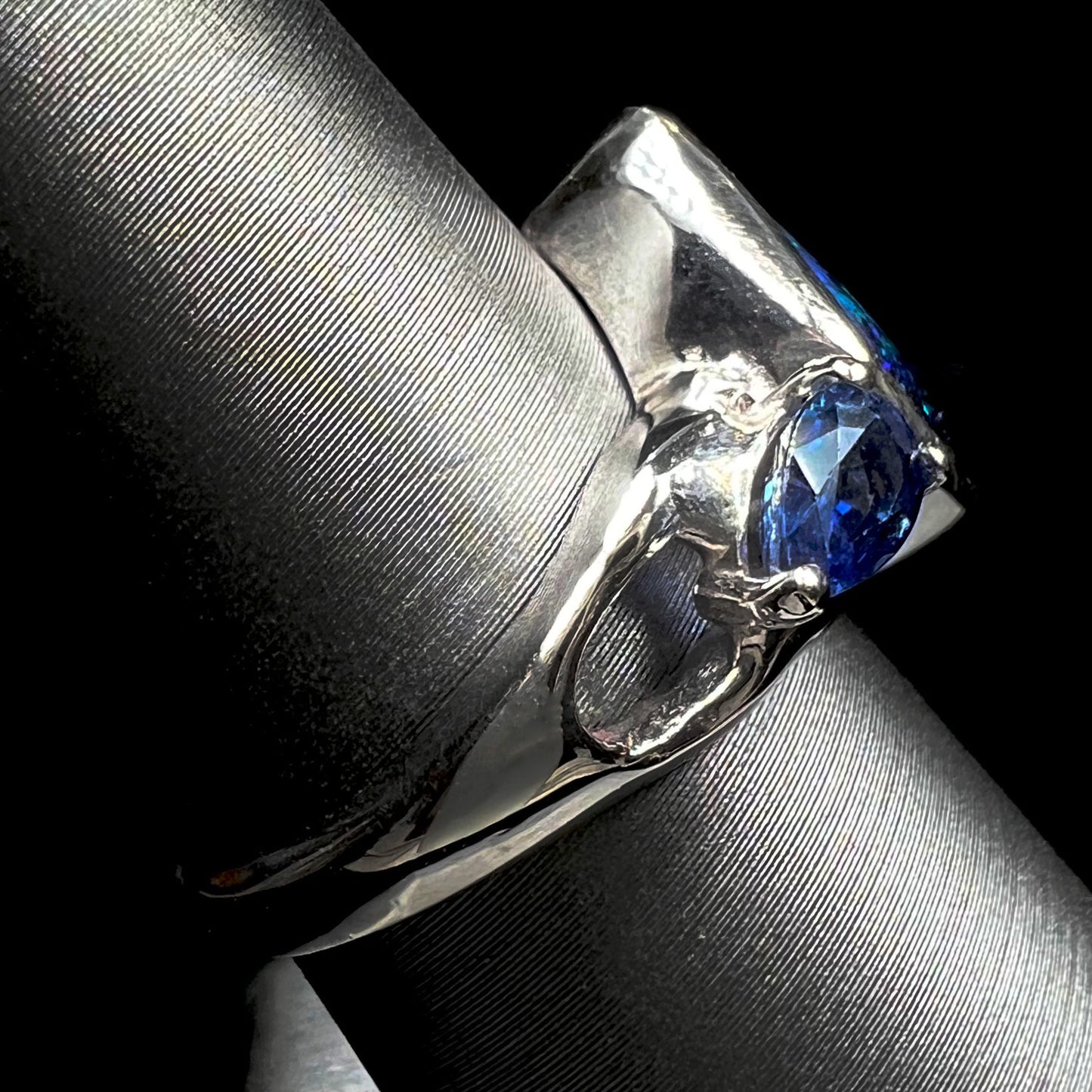 A ladies' white gold ring set with Australian black boulder opal and pear shape blue sapphire.