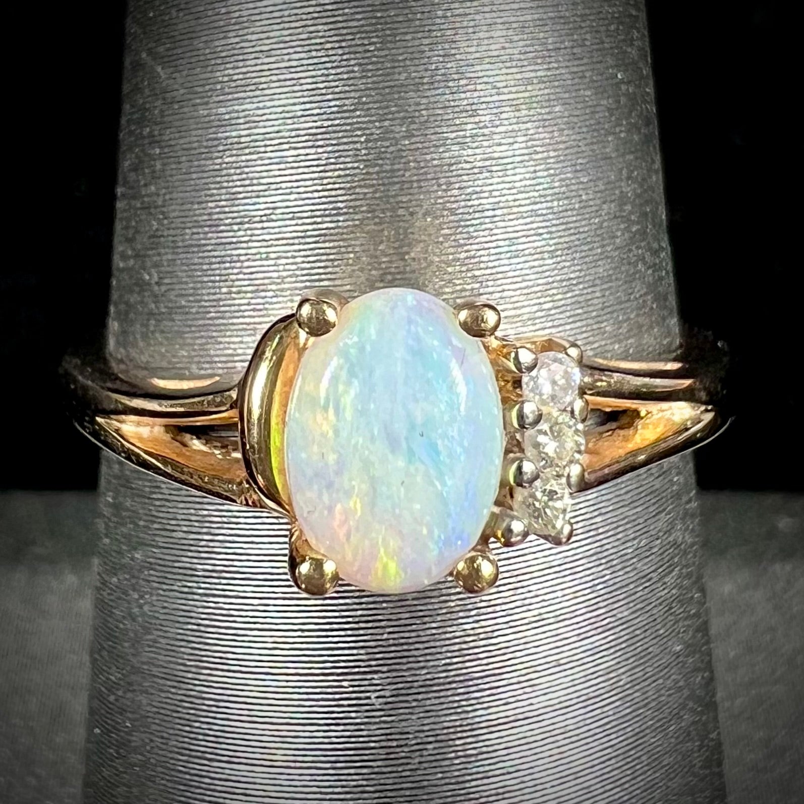 A ladies' yellow gold Coober Pedy, Australian opal ring set with three round cut diamonds.