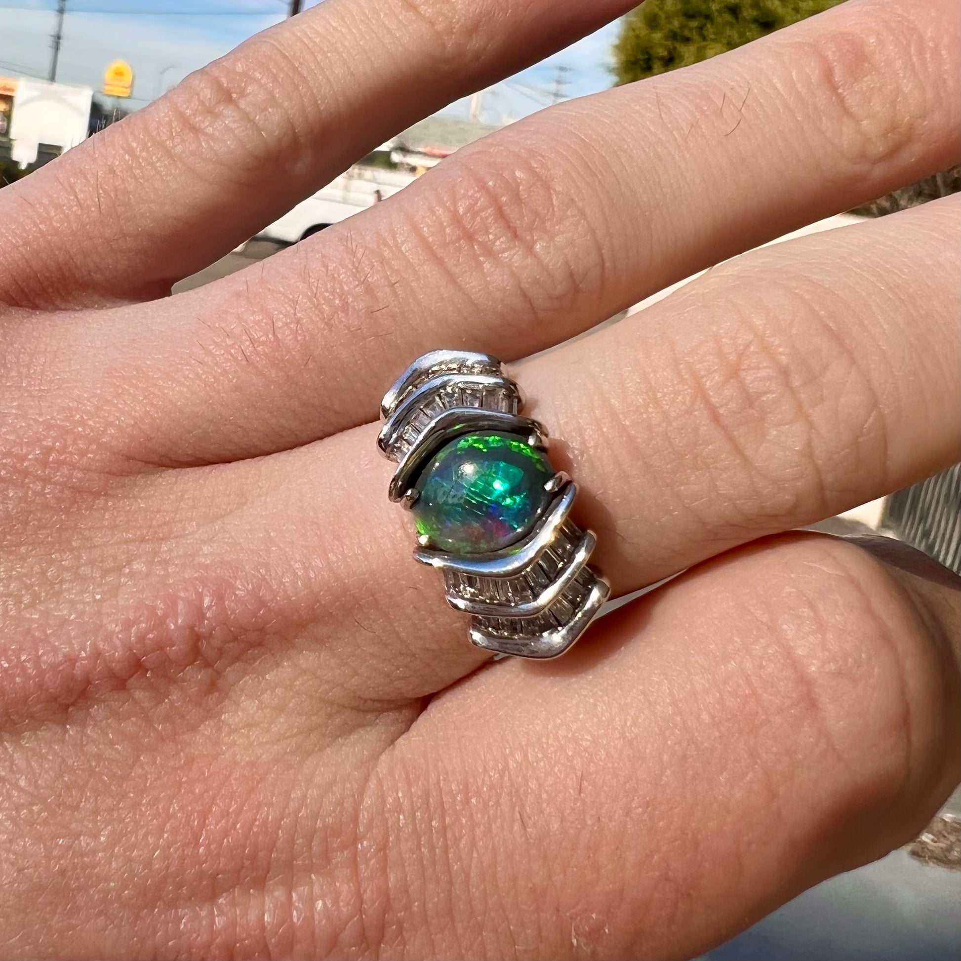 A white gold ring set with a Lightning Ridge black opal and baguette cut diamonds.