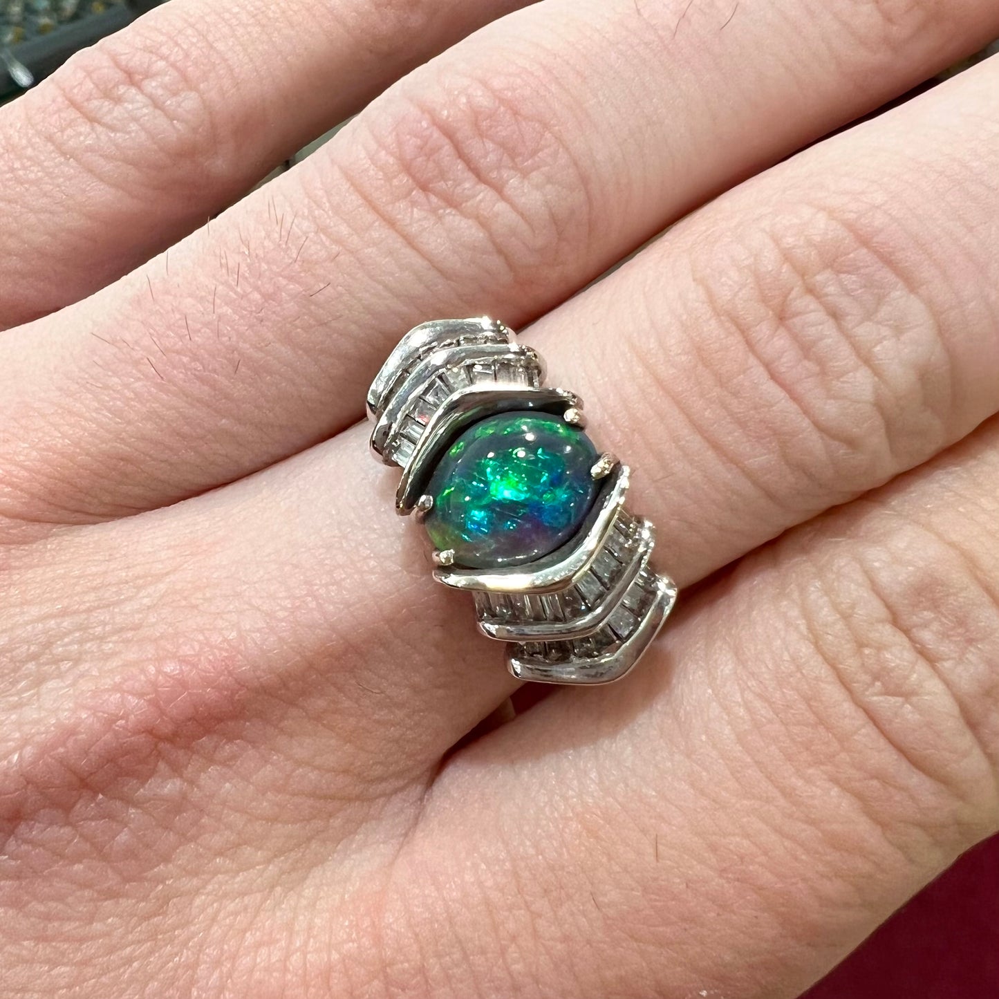 A white gold ring set with a Lightning Ridge black opal and baguette cut diamonds.