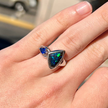 A ladies' white gold ring set with Australian black boulder opal and pear shape blue sapphire.