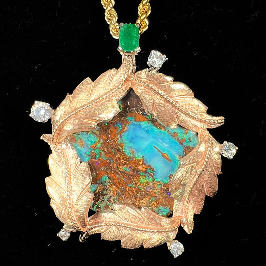 A gold opalized wood, diamond, and emerald pendant.  The opal is set in a wreath of gold feathers that form a star.