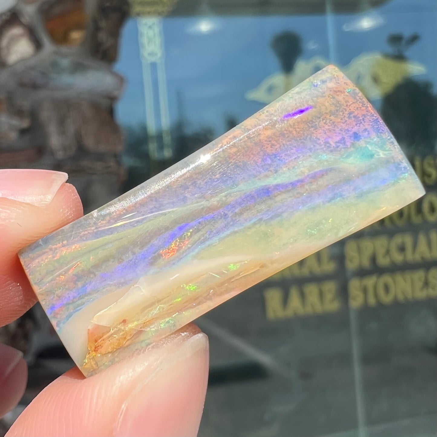 A polished, tapered rectangular cut boulder opal stone from Quilpie, Australia.