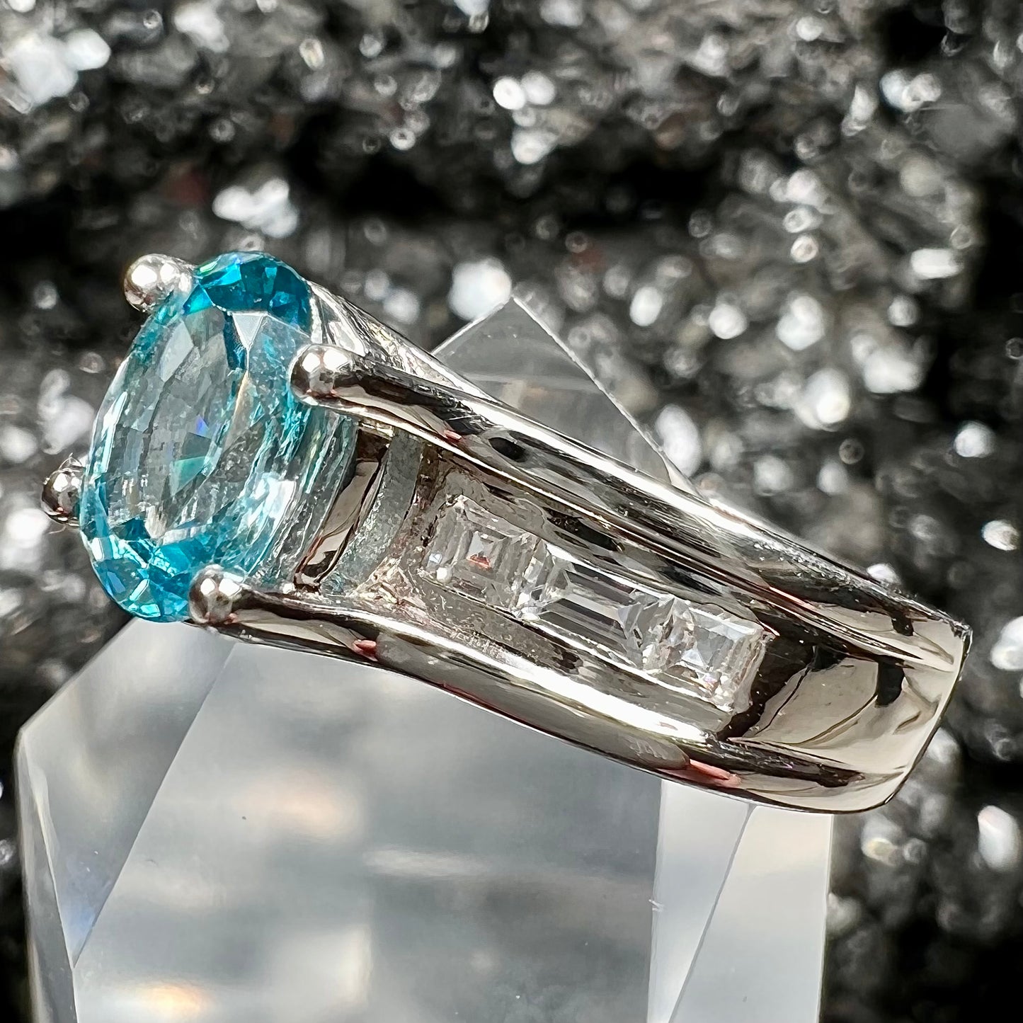 A sterling silver ring set with an oval cut blue zircon center stone and channel set white zircon accents.