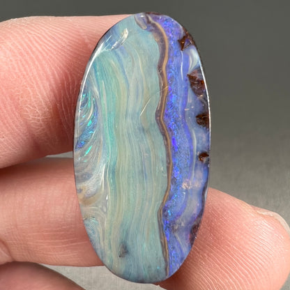 A loose, oval cabochon cut boulder opal stone from Queensland, Australia.