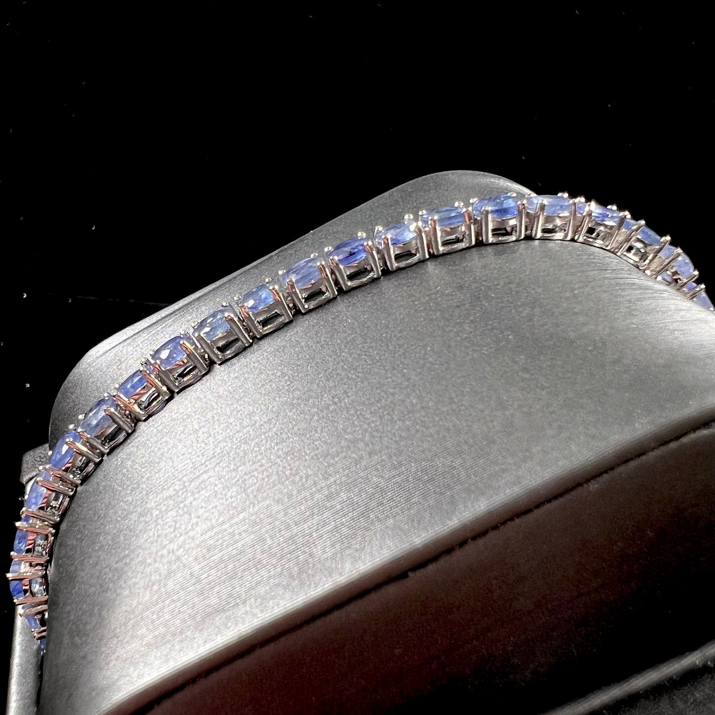 A sterling silver tennis bracelet set with faceted oval cut blue sapphires.