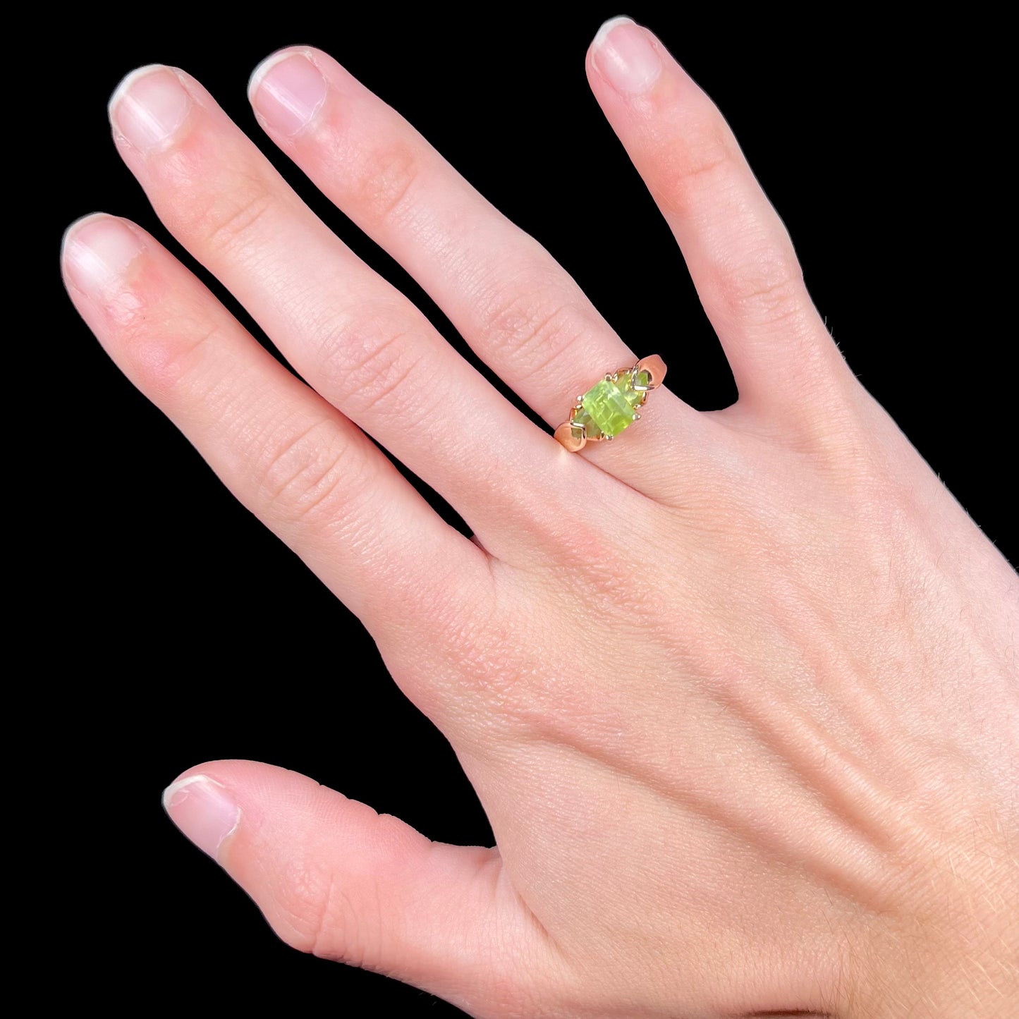 A ladies' three stone peridot ring in yellow gold.  The center stone is emerald cut, and the side stones are pear shaped.