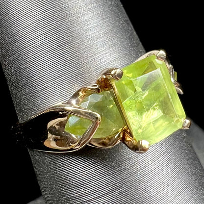 A ladies' three stone peridot ring in yellow gold.  The center stone is emerald cut, and the side stones are pear shaped.