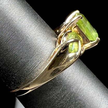 A ladies' three stone peridot ring in yellow gold.  The center stone is emerald cut, and the side stones are pear shaped.