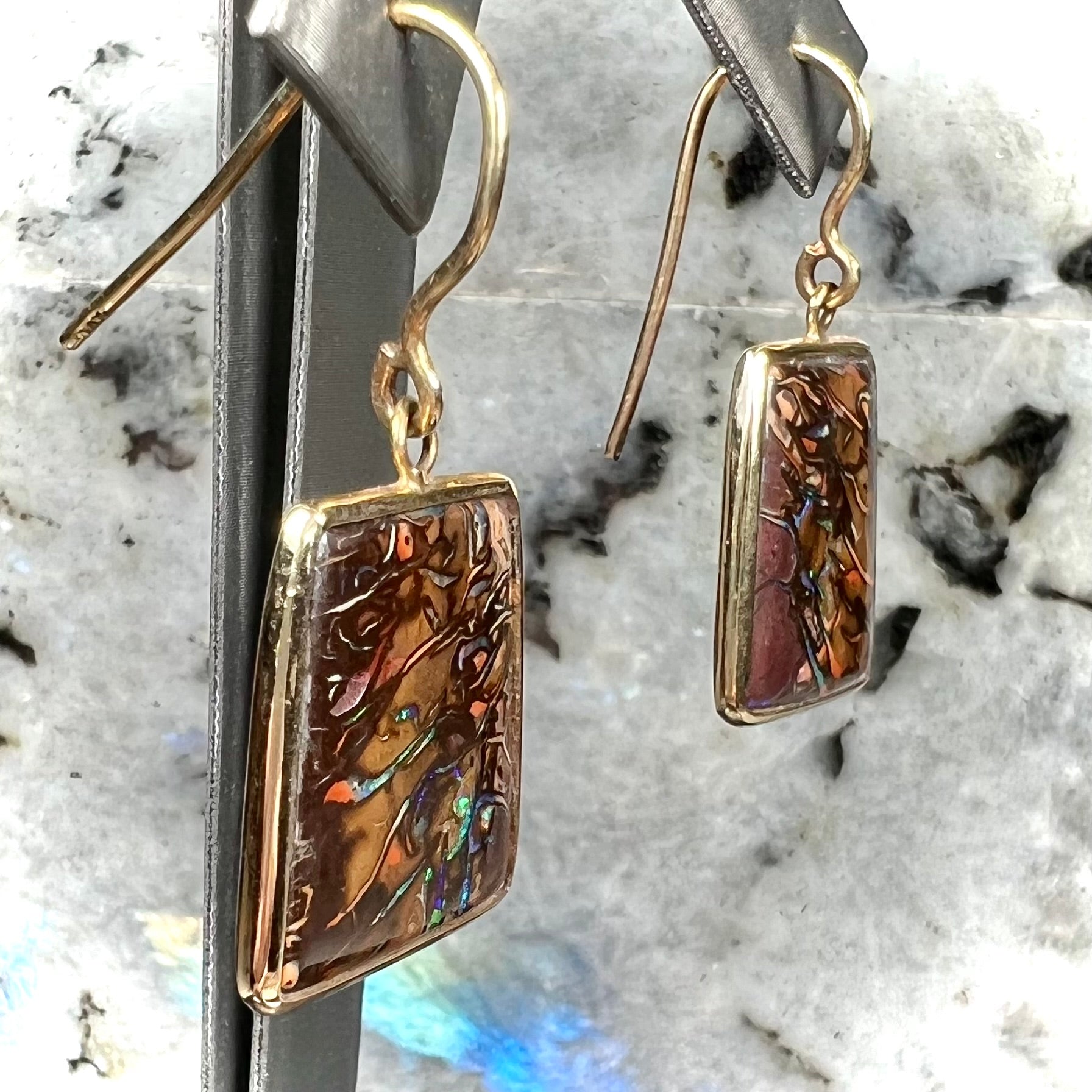 A pair of yellow gold French wire dangle earrings set with Koroit boulder opal.