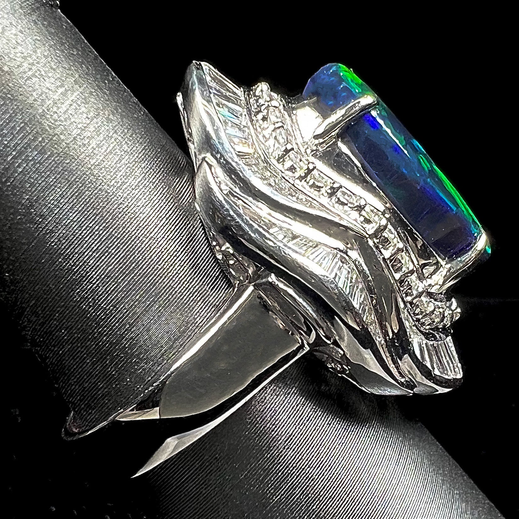 A ladies' platinum diamond halo ring set with a natural black opal stone from Lightning Ridge, Australia.