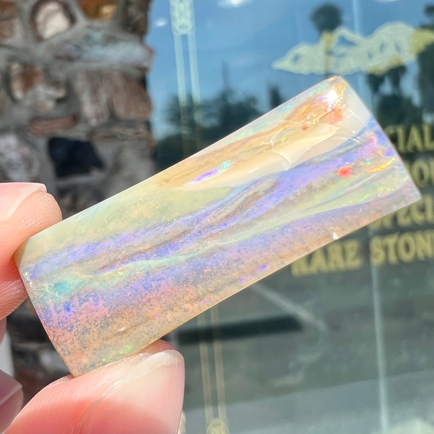 A polished, tapered rectangular cut boulder opal stone from Quilpie, Australia.