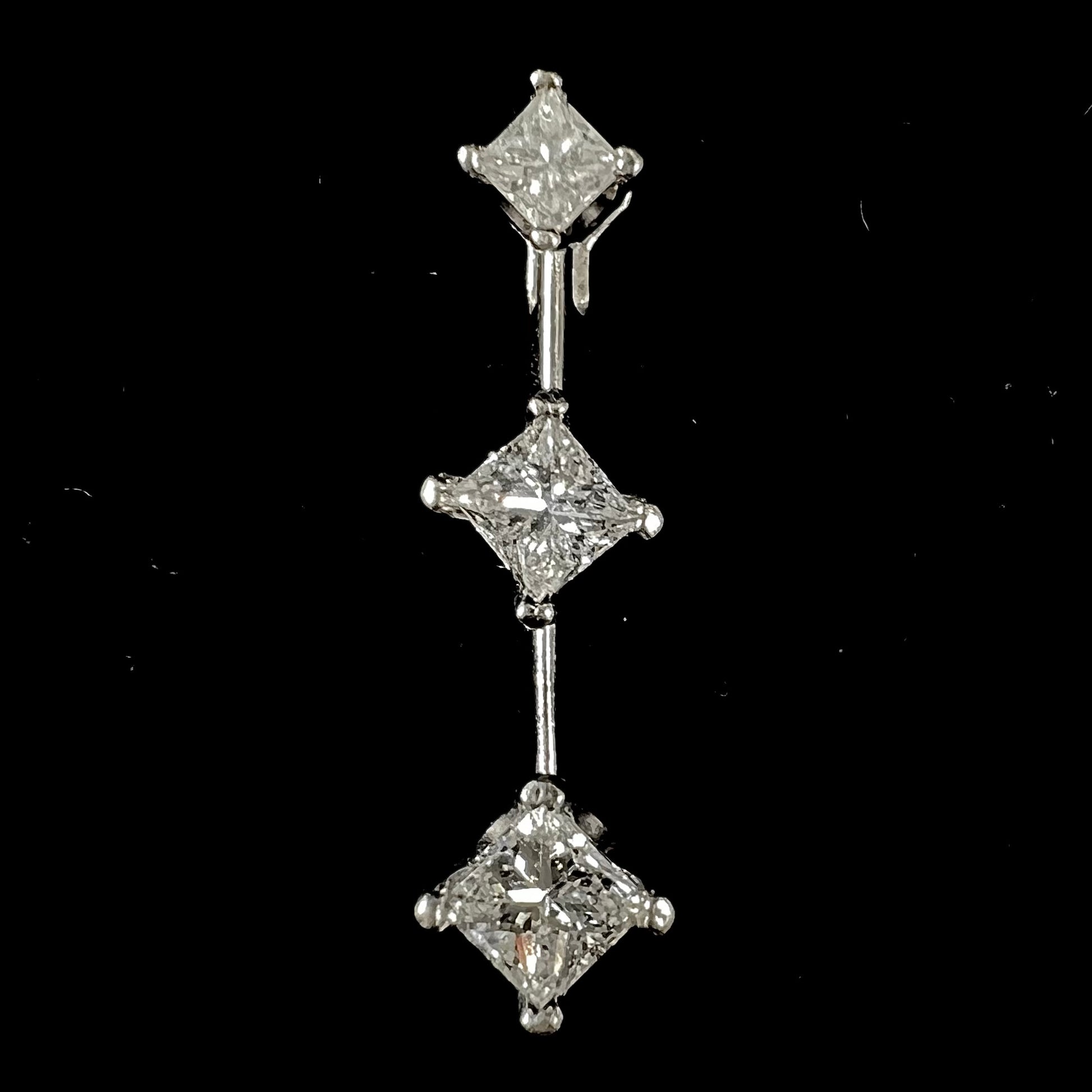 A ladies' white gold three stone drop pendant set with princess cut diamonds.  There are two points of articulation.