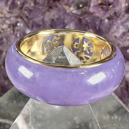 A stone ring carved from purple jadeite jade and mounted on a gold band.