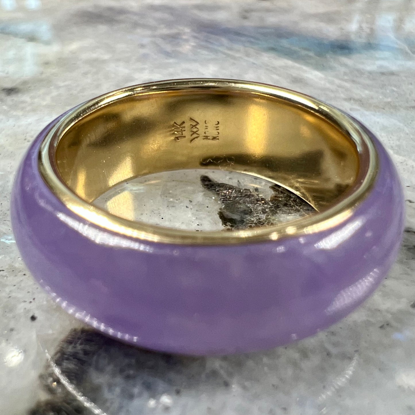 A stone ring carved from purple jadeite jade and mounted on a gold band.