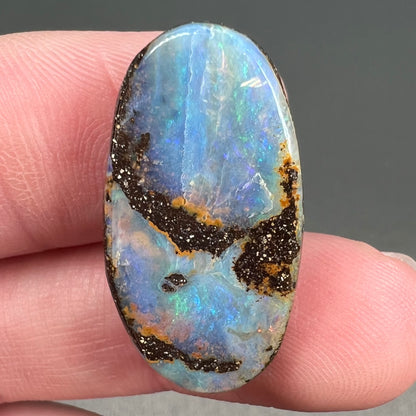 A loose, oval cabochon cut boulder opal stone from Queensland, Australia.