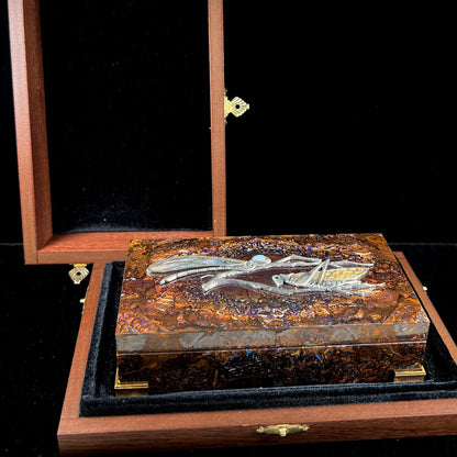 A stone box made from Koroit, Australian boulder opal featuring the motif of a dragonfly and cricket made from sterling silver, set with yellow diamonds, an emerald, and a crystal opal.