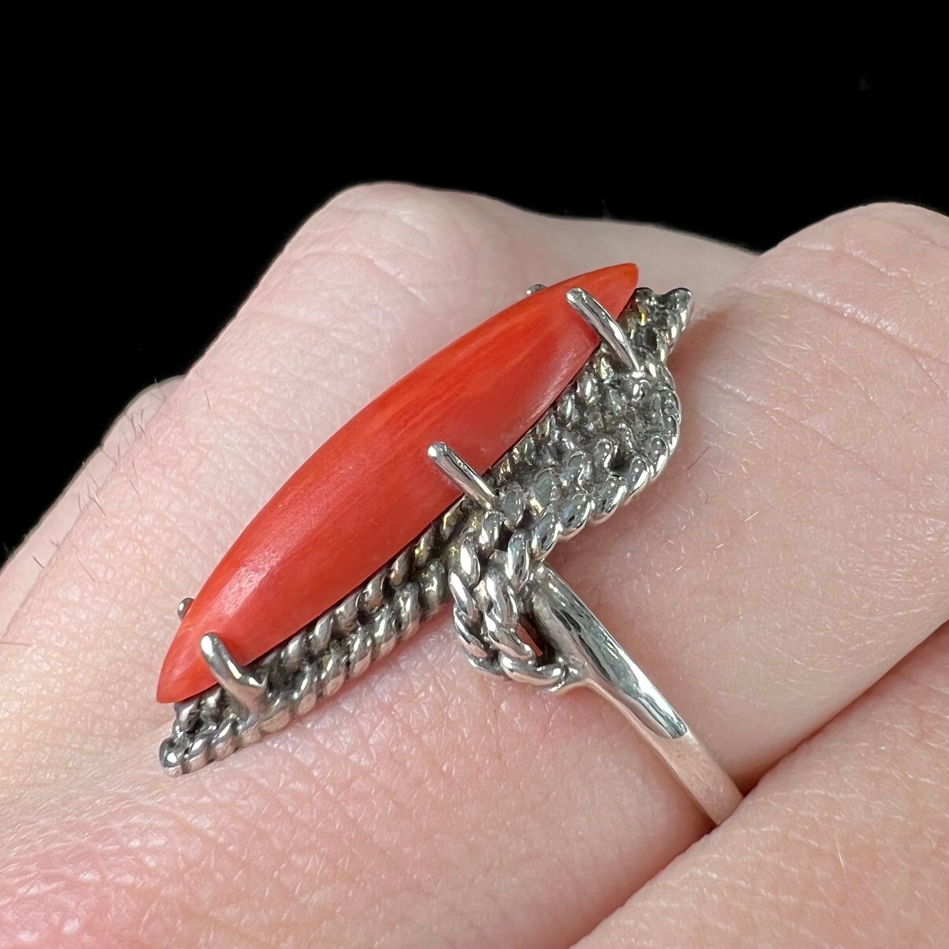 A prong-set silver ring set with a red marquise cut coral.