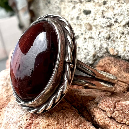 A men's sterling silver rope bezel ring set with a red tiger's eye stone.