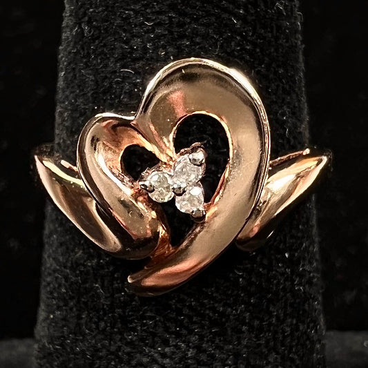 A rose gold heart ring set with three round cut diamonds.