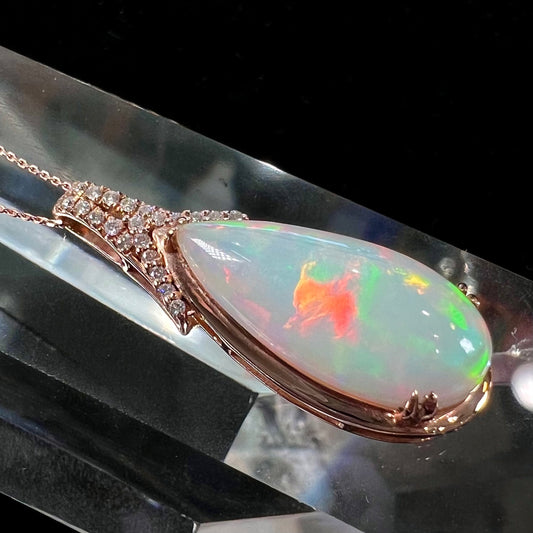 A rose gold, teardrop shaped fire opal and diamond necklace on a cable chain.