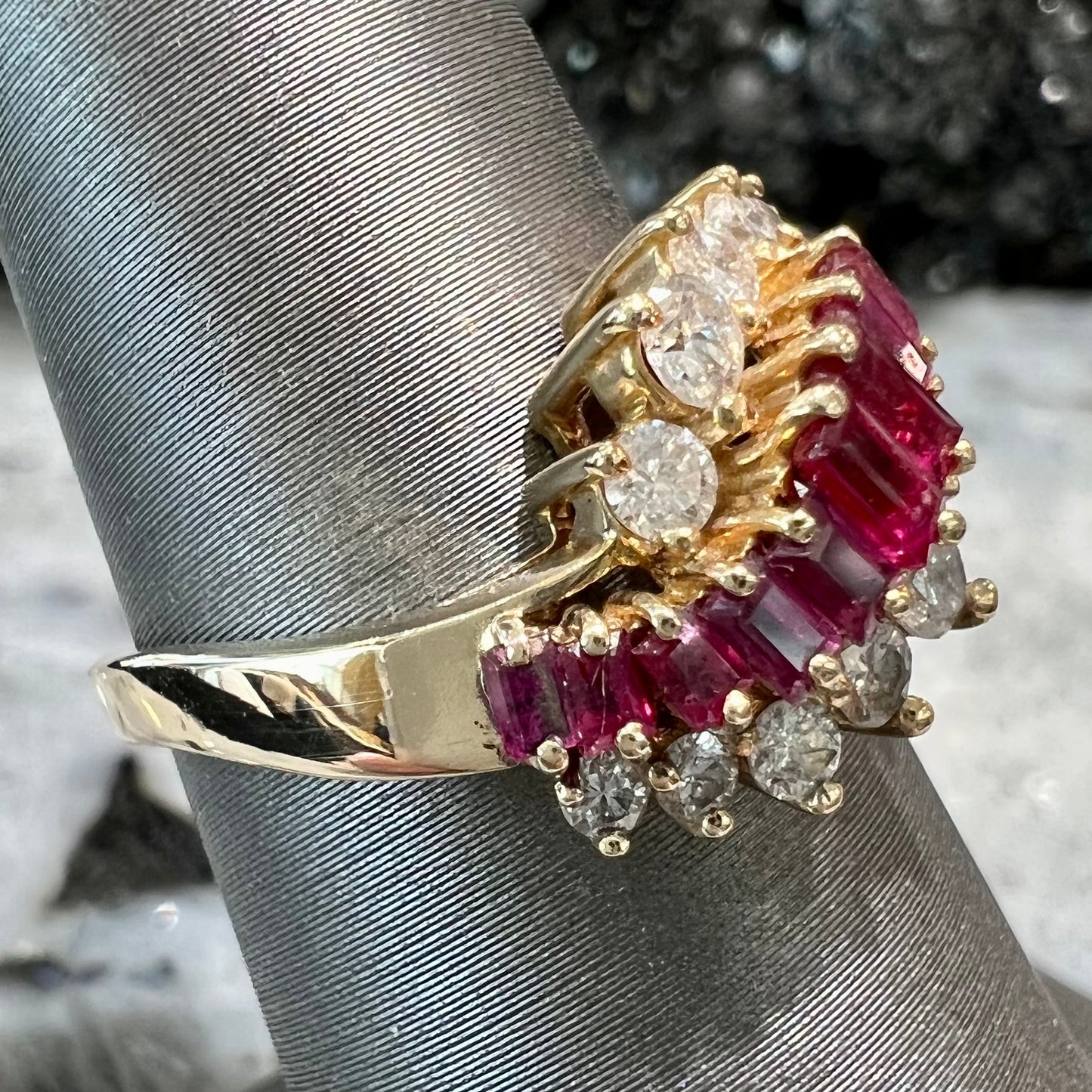 A yellow gold ladies' ring set with 12 baguette cut rubies and 12 Standard Round Brilliant Cut diamonds.