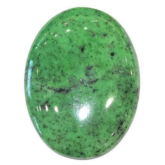 A loose, oval cabochon cut green zoisite stone with black spots.