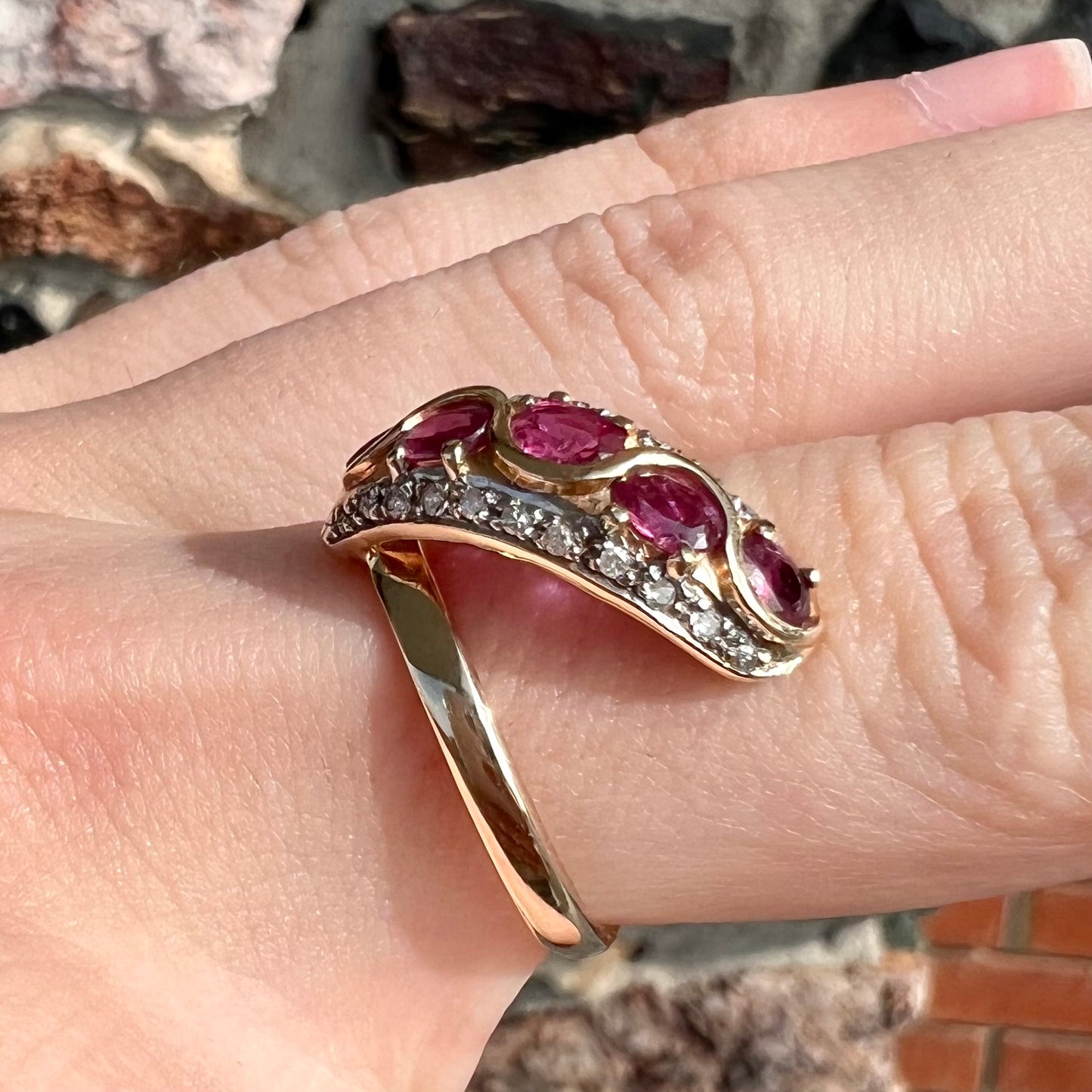 A custom freeform design yellow gold twisted shank ring set with five oval cut rubies and small round diamonds.