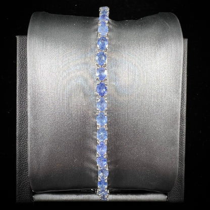 A sterling silver tennis bracelet set with faceted oval cut blue sapphires.